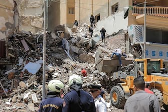 Civil defence first responders speak with a policeman (white) at the scene of a collapsed 13-storey-building in the Sidi Bishr district of Egypt's northern city of Alexandria on June 26, 2023. (Photo by Hazem GOUDA / AFP)