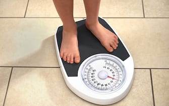 8 year old boy weighing himself on bathroom scales at home