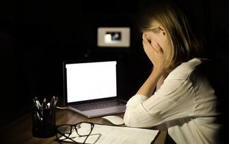 Depressed woman working with computer at night