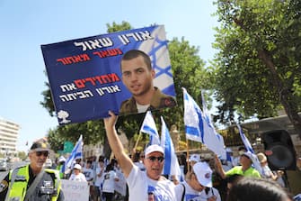 epa07763613 Protester hold a picture of Israeli soldier Oron Shaul, whose body is held by the Palestinian Hamas militant group in the Gaza Strip, during a protest to call on the Prime Minister to 'return bodies of soldiers captured by Hamas' in front of Prime Minister Benjamin Netanyahu's residence in Jerusalem, Israel, 09 August 2019. Media reports that First Sergeant Oron Shaul and Lieutenant Hadar Goldin were killed in a battle during the 2014 Israel-Gaza conflict and their bodies had since been held by Hamas. Families urge prime minister to return the bodies home.  EPA/ABIR SULTAN