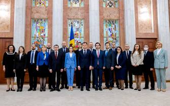 epa10471173 President of Moldova Maia Sandu (C, in light blue) with President of the Parliament Igor Grosu (C-L) and new Prime Minister Dorin Recean (C-R), along with new ministers, pose for a family photograph after a swearing-in ceremony for the new government at the presidential palace in Chisinau, Moldova, 16 February 2023. Moldova's parliament approved Dorin Recean as prime minister on 16 February to lead a pro-Western government.  EPA/DUMITRU DORU