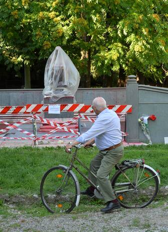Statua Indro Montanelli transennata e coperta in attesa di pulizia, cittadini portano fiori e biglietti, Polizia Locale in presidio