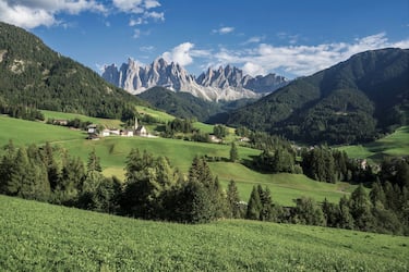 Green grassy meadows in the village of Santa Maddalena against the great peaks of the Odle Group, Val di Funes, Dolomites.