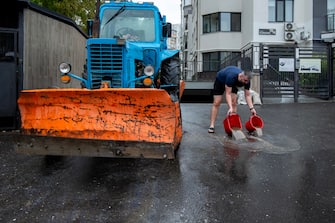 epa11605476 A man empties buckets of water collected in a flooded parking lot amid heavy rains in Chisinau, Moldova, 15 September 2024. Floods caused by heavy rains have been battering central and eastern Europe since 13 September, with at least four dead in Romania, four missing in the Czech Republic, and alarming water levels recorded in Poland.  EPA/DUMITRU DORU