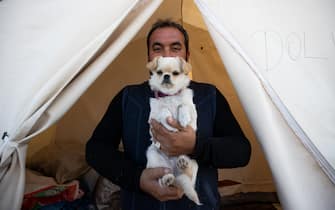KAHRAMANMARAS, TURKIYE - FEBRUARY 24: Cuma Caglarsu, an earthquake survivor lives the tent city established in Vali Saim Cotur Stadium and around with his dog named "Matilda" after 7.7 and 7.6 magnitude earthquakes hit multiple provinces of Turkiye including Kahramanmaras on February 24, 2023. Some survivors of earthquakes in Kahramanmaras live together in a tent city with their animals, such as fish, birds, partridges, cats and dogs, which they rescued while leaving their homes. Established by the Sakarya 7th Commando Brigade Command, the tent city hosts nearly 3,500 earthquake victims as well as dozens of pets. (Photo by Fatih Kurt/Anadolu Agency via Getty Images)