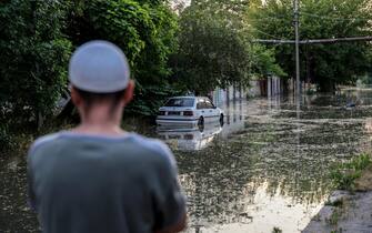 epa10676371 A man looks on as a car is parked in a flooded street of Kherson, Ukraine, 06 June 2023.Ukraine has accused Russian forces of destroying a critical dam and hydroelectric power plant on the Dnipro River in the Kherson region along the front line in southern Ukraine on 06 June. A number of settlements were completely or partially flooded, Kherson region governor Oleksandr Prokudin said on telegram. Russian troops entered Ukraine on 24 February 2022 starting a conflict that has provoked destruction and a humanitarian crisis.  EPA/IVAN ANTYPENKO