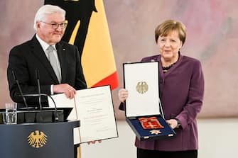epaselect epa10577208 Former German Chancellor Angela Merkel (R) poses with the box after she was awarded the 'Grand Cross of the Order of Merit of the Federal Republic of Germany' by German President Frank-Walter Steinmeier (L) during a ceremony in Berlin, Germany, 17 April 2023.  EPA/FILIP SINGER