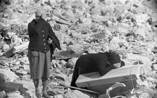 An elderly woman stands by as another woman collapses in tears among the rubble, Longarone, near the Vajont Dam in the Piave Valley, Italy, early October, 1963. On October 9, a landslide in the dam basin caused a wave more than 800 feet high to overtop the dam and flood the valley below--five villages were completely destroyed, more than 2000 people were killed, and thousands more were left homeless and displaced. (Photo by Archivio Cameraphoto Epoche/Getty Images)