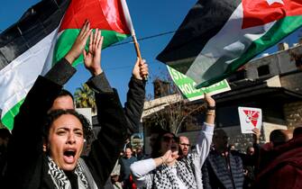 People wave Palestinian and Jordanian flags and chant slogans as they march during a demonstration near the US embassy in the capital Amman in solidarity with the people of Gaza on December 15, 2023, amid the continuing battles between Israel and the militant group Hamas. (Photo by Khalil MAZRAAWI / AFP)