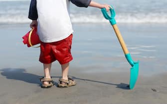 A small boy pauses to watch the surf while playing at Hampton Beach, New Hampshire, USA.