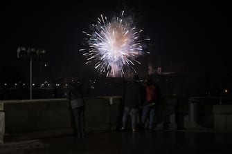 epa10384655 People watch fireworks from the Federal terrace (Bundesterrasse) during New Year's Eve celebrations in Bern, Switzerland, 01 January 2023.  EPA/ANTHONY ANEX