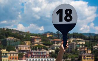 SANTA MARGHERITA LIGURE, ITALY - MAY 19, 2018:Tour Guide hand holding tor part identification board with tour Number on with defocused background