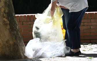 Anziani cercano oggetti in sacchetti della spazzatura a Milano