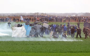 Protesters, surrounded by tear gas, clash with riot mobile gendarmes during a demonstration called by the collective "Bassines non merci", the environmental movement "Les Soulevements de la Terre" and the French trade union 'Confederation paysanne' to protest against the construction of a new water reserve for agricultural irrigation, in Sainte-Soline, central-western France, on March 25, 2023. - More than 3,000 police officers and gendarmes have been mobilised and 1,500 "activists" are expected to take part in the demonstration, around Sainte-Soline. The new protest against the "bassines", a symbol of tensions over access to water, is taking place under thight surveillance on March 25, 2023 in the Deux-Sevres department. (Photo by Yohan Bonnet / AFP) (Photo by YOHAN BONNET/AFP via Getty Images)