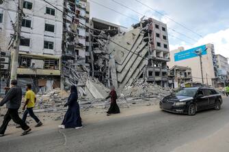 epa10922145 Palestinians walk past buildings destroyed in recent Israeli strikes in Al Remal, in Gaza City, 16 October 2023. Israel has warned all citizens of the Gaza Strip to move to the south ahead of an expected invasion. More than 2,750 Palestinians and 1,400 Israelis have been killed according to the Israel Defense Forces (IDF) and Palestinian Health Ministry after Hamas militants launched an attack against Israel from the Gaza Strip on 07 October.  EPA/MOHAMMED SABER