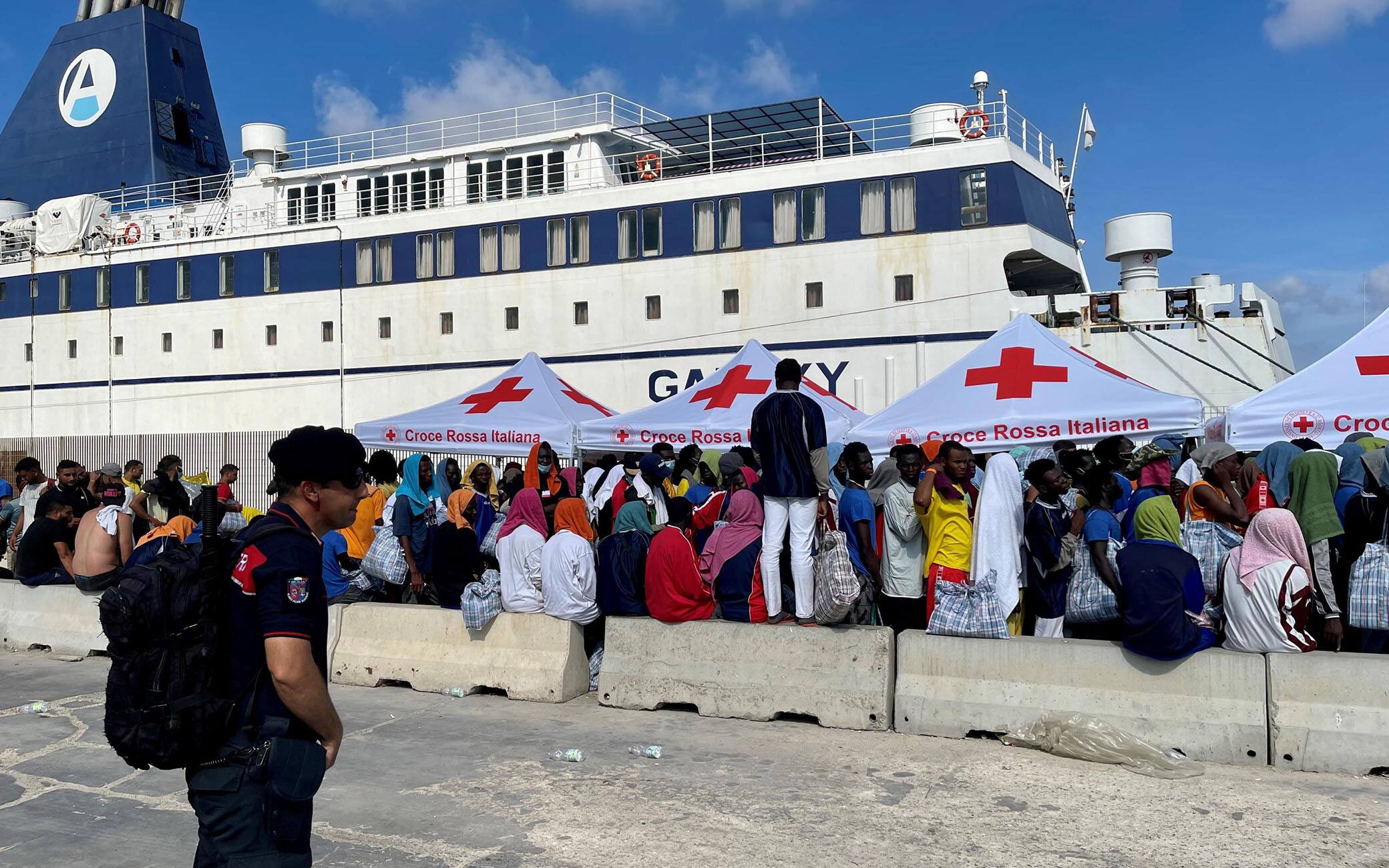 A group of migrants wait on the island of Lampedusa as Italian authorities prepare for transferring people following new arrivals, Italy, 13 September 2023. More than 6,790 migrants were on the Italian island on 13 September after a record arrival of 6,402 people in two days. The Prefecture of Agrigento has arranged for a ferry to pick up around 700 people from Lampedusa to Porto Empedocle, while another 180 being transferred by an IOM flight. ANSA/ELIO DESIDERIO