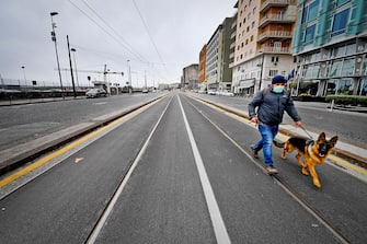 Daily life in Naples, Italy,  during the coronavirus emergency lockdown. A man takes his dog for a walk in the empty tramway lane, like the streets on the sides, for the traffic blockade decided by the Government to avoid contagion from Covid-19, 25 march 2020
ANSA / CIRO FUSCO