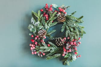 Beautiful Christmas wreath on background. Christmas composition. Wreath made of christmas tree branches and lighting garlands on grey background.