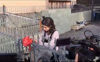Un fermo immagine tratto da un video mostra Elena Cecchettin mettere fiocchi rossi sul cancello per festeggiare la laurea che la sorella Giulia avrebbe dovuto discutere oggi, 16 novembre 2023. ANSA/ MICHELE GALVAN