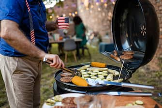 A senior man grilling food for American national holiday in a back yard