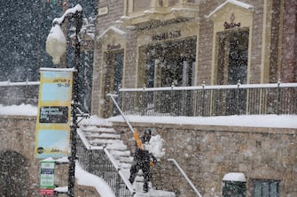 epa11086071 A man shovels snow on Old Main Street the day before the start of the 2024 Sundance Film Festival in Park City, Utah, USA, 17 January 2024. The festival runs from 18-28 January 2024.  EPA/George Frey