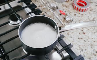Close-up of milk boiling in a pot on gas cooktop