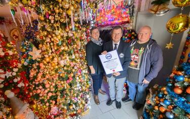 30 November 2023, Lower Saxony, Rinteln: Susanne and Thomas Jeromin stand with Olaf Kuchenbecker (M) from the Record Institute for Germany surrounded by Christmas trees in their house in the district of Schaumburg. 555 Christmas trees and almost 108,000 Christmas baubles: During Advent, the Jeromin family's house shines as a colorful Christmas world. The Record Institute for Germany has awarded the family "for the most decorated Christmas trees in one place". Photo: Julian Stratenschulte/dpa (Photo by Julian Stratenschulte/picture alliance via Getty Images)