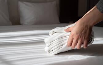 Conceptual of female chambermaid making bed in hotel room.