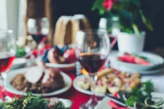 Blurred background of festive table setting for holiday dinner with dishes. Family together Christmas or New Year celebration concept. Copy space.