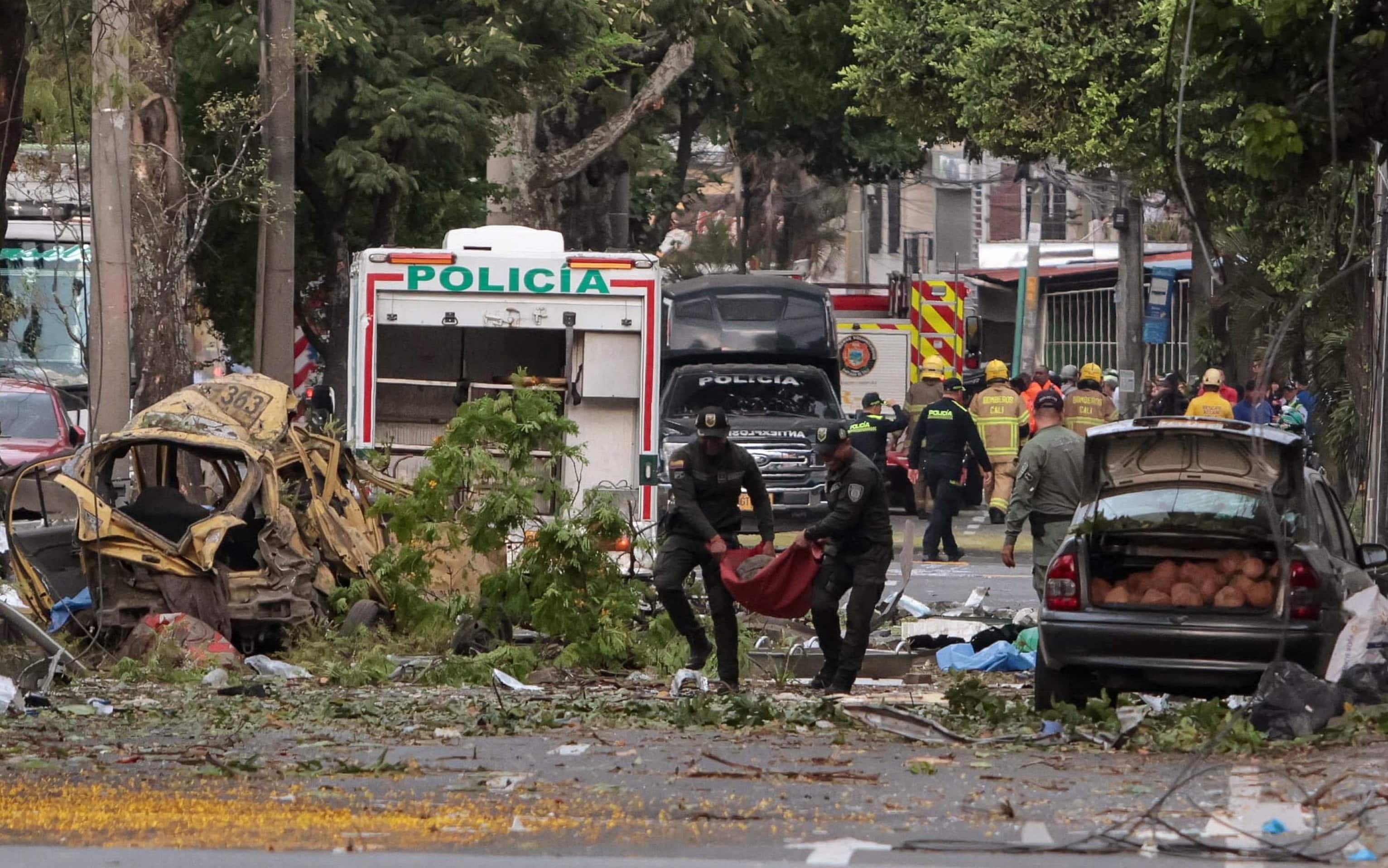 TOPSHOT - Police officers carry debris from the site of a bomb explosion in Cali, Colombia on August 21 2025. Five people were killed and dozens were injured when a vehicle bomb targeted a military base on a busy street in the Colombian city of Cali on August 21, 2025, local authorities said. (Photo by Iusef Samir Rojas / AFP)