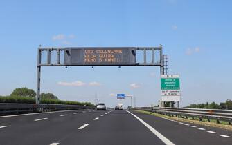 motorway sign with the inscription in Italian which means that points are deducted from the driving license if the driver drives the car with a mobile phone in italian language