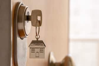 CLOSE UP OF KEY AND HOUSE KEYCHAIN â  â  IN HIGH SECURITY DOOR LOCK. HOME INSURANCE CONCEPT. COPY SPACE.
