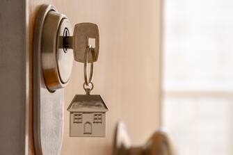 CLOSE UP OF KEY AND HOUSE KEYCHAIN â  â  IN HIGH SECURITY DOOR LOCK. HOME INSURANCE CONCEPT. COPY SPACE.