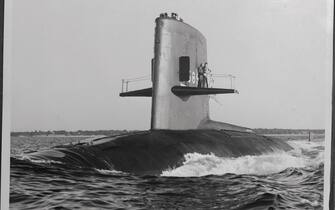 (Original Caption) Plowing through the waters of Long Island Sound on her maiden voyage is the Scorpion, the Navy's newest atomic powered submarine. Standing on the diving plane are Vice Admiral Hyman G. Rickover, Lt. and Commander James F. Calvert, and the sub's skipper, Cmdr. Norman Bessac is on the bridge. Built by the electric boat division of General Dynamics, the Scorpion is a sister ship of the Skipjack, which the Navy says is the world's fastest submarine.