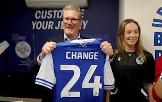 BRISTOL, ENGLAND - JUNE 17:  Labour Party leader Keir Starmer (L) holds a Bristol Rovers jersey with Amelia Griffiths as he visit Bristol Rovers FC during a general election campaign event at Memorial Stadium on June 17, 2024 in Bristol, England. If The Labour Party wins the next General Election they plan to reform football governance and put the fans front and centre of the future of English Football.  (Photo by Geoff Caddick/Getty Images)