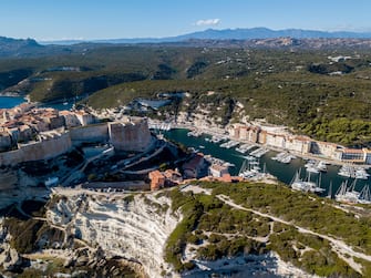 Aerial view of Bonifacio old town built on cliffs of white limestone, cliffs. Harbor. Corsica, France. Strait of Bonifacio