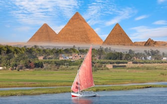 Beautiful Nile scenery with traditional Felluca sailing boat in the Nile on the way to Giza pyramids - Cairo, Egypt