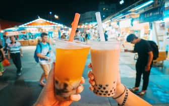 Tourists' hands holding Taiwanese bubble tea at Dongdamen Night Market, Hualien, Taiwan