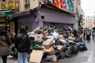 Pedestrians walk past waste that has been piling up on the pavement as waste collectors are on strike since March 6 against the French government's proposed pensions reform, in Paris on March 13, 2023. (Photo by ALAIN JOCARD / AFP) (Photo by ALAIN JOCARD/AFP via Getty Images)