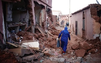 epa10853311 A woman passes by damaged buildings following a powerful earthquake in Ouirgane, south of Marrakesh, Morocco, 10 September 2023. A magnitude 6.8 earthquake that struck central Morocco late 08 September has killed at least 2,012 people and injured 2,059 others, 1,404 of whom are in serious condition, damaging buildings from villages and towns in the Atlas Mountains to Marrakesh, according to a report released by the country's Interior Ministry. The earthquake has affected more than 300,000 people in Marrakesh and its outskirts, the UN Office for the Coordination of Humanitarian Affairs (OCHA) said.  EPA/YOAN VALAT