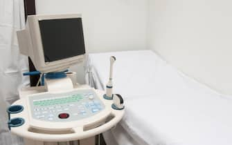 Examination bed with ultrasound scanner machine in medical center hospital