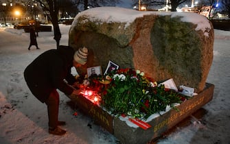 A man places a lit candle at a makeshift memorial for late Russian opposition leader Alexei Navalny organized at the monument to the victims of political repressions in Saint Petersburg on February 16, 2024, following Navalny's death in his Arctic prison. (Photo by Olga MALTSEVA / AFP)
