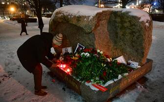 A man places a lit candle at a makeshift memorial for late Russian opposition leader Alexei Navalny organized at the monument to the victims of political repressions in Saint Petersburg on February 16, 2024, following Navalny's death in his Arctic prison. (Photo by Olga MALTSEVA / AFP)