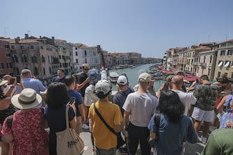 VENICE, ITALY - AUGUST 02: Tourists flock to the Rialto Bridge on August 02, 2023 in Venice, Italy. UNESCO officials have included Venice and its lagoon to the list of world heritage in danger to review, along with Ukraine's Kyiv, and Lviv. The UN cultural agency deems Italy not effective in protecting Venice from mass tourism and extreme weather conditions. (Photo by Stefano Mazzola/Getty Images)