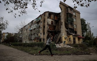 (FILES) A man runs in front of a destroyed apartment building in Bakhmut, Donetsk region, on September 26, 2022, amid Russia's invasion of Ukraine. Russia's private army Wagner claimed on May 20, 2023, the total control of the east Ukrainian city of Bakhmut, the epicentre of fighting, as Kyiv said the battle was continuing but admitted the situation was "critical". Bakhmut, a salt mining town that once had a population of 70,000 people, has been the scene of the longest and bloodiest battle in Moscow's more than year-long Ukraine offensive. The fall to Russia of Bakhmut, where both Moscow and Kyiv are believed to have suffered huge losses, would have high symbolic value. (Photo by ANATOLII STEPANOV / AFP)