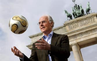 World Cup organising committee chief Franz Beckenbauer showcases the golden football developed especially for the final of the upcoming World Cup in front of Berlin's Brandenburg Gate, Germany Tuesday 18 April 2006. 
ANSA/PEER GRIMM