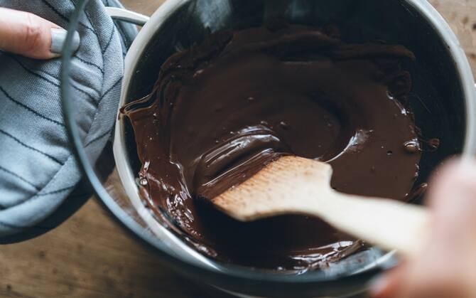 Chocolate pudding in wooden spoon on the cooker