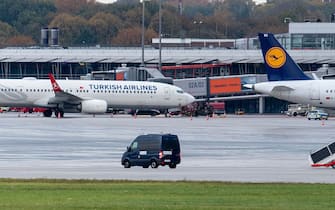 A police van observe the car of a hostage taker seen parked under a Turkish airline plane on the tarmac at the airport in Hamburg, northern Germany on November 5, 2023. Air traffic at Hamburg airport remained suspended Sunday over a suspected hostage situation on the tarmac involving a child, local authorities said.
A gunman rammed his car through the security area onto the apron where planes are parked on Saturday evening, firing two shots in the air and flinging two burning bottles out of the vehicle, police said. (Photo by NEWS5 / Schröder / NEWS5 / AFP) (Photo by NEWS5 / SCHRODER/NEWS5/AFP via Getty Images)