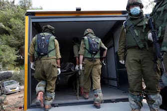 epa10911392 Israeli soldiers take the bodies of Israelis killed in Kfar Aza kibbutz near the border with Gaza, 10 October 2023. More than 900 people have been killed, around 150 were taken as hostages, and 1,500 others injured, according to Israel Defence Forces (IDF), after the Islamist movement Hamas launched an attack against Israel on 07 October. More than 3,000 people, including 1,500 militants from Hamas, have been killed and thousands injured in Gaza and Israel since 07 October, according to Israeli military sources and Palestinian officials.  EPA/ATEF SAFADI