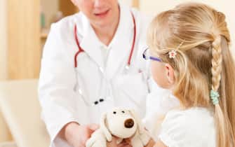 Doctor - Pediatrician - with a child patient in his practice, she is giving him her soft toy as to thank him
